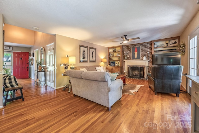 302 Redwood Pl, Lenoir, NC 28645 - living room featuring light wood-type flooring, ceiling fan, a brick fireplace, built in features, and a textured ceiling