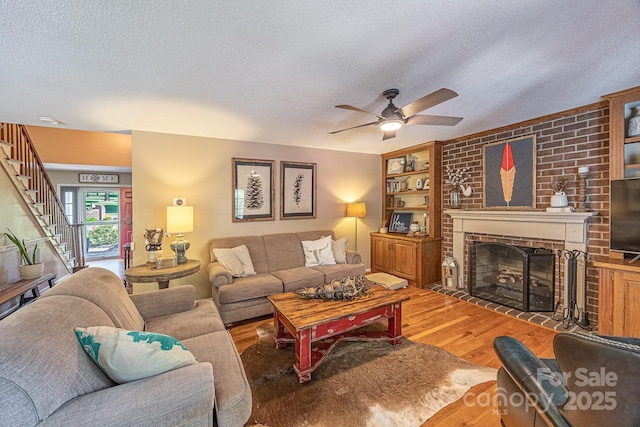 302 Redwood Pl, Lenoir, NC 28645 - living room with a textured ceiling, wood finished floors, a brick fireplace, ceiling fan, and stairs
