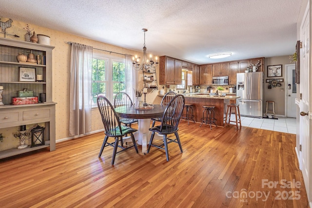 302 Redwood Pl, Lenoir, NC 28645 - dining room with light wood-type flooring, a textured ceiling, and a chandelier