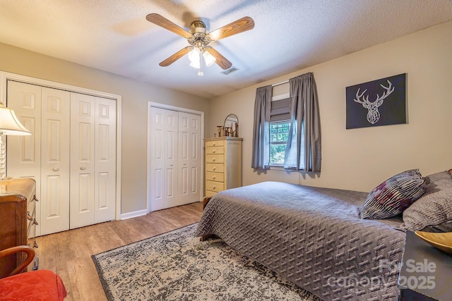 302 Redwood Pl, Lenoir, NC 28645 - bedroom featuring two closets, wood finished floors, ceiling fan, and a textured ceiling