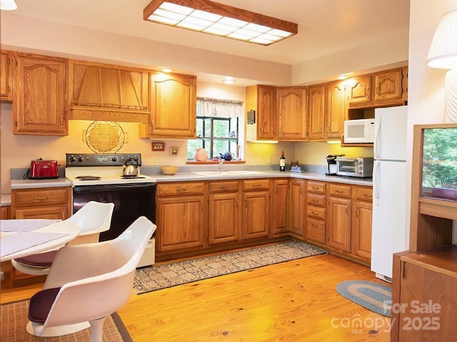 1090 Woolyshot Branch Rd, Hot Springs, NC 28743 - kitchen featuring white appliances, light wood-style floors, light countertops, and brown cabinetry