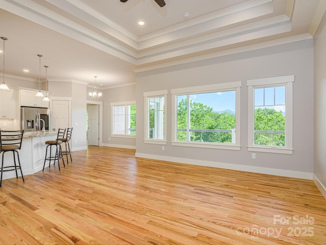 62 Sharp Rd W, Black Mountain, NC 28711 - unfurnished living room with ornamental molding, light wood-style flooring, a raised ceiling, a ceiling fan, and a chandelier
