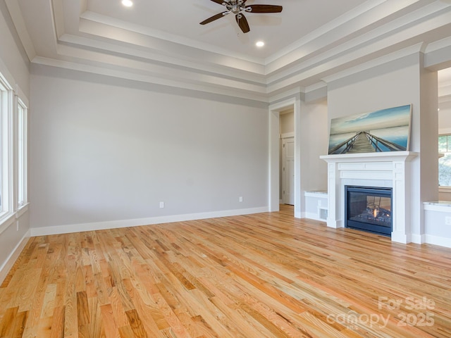 62 Sharp Rd W, Black Mountain, NC 28711 - unfurnished living room featuring a tray ceiling, ceiling fan, light wood-style flooring, ornamental molding, and a glass covered fireplace