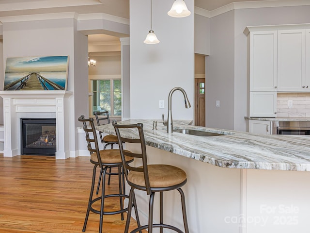 62 Sharp Rd W, Black Mountain, NC 28711 - kitchen featuring light wood-style floors, a glass covered fireplace, light stone counters, ornamental molding, and white cabinets