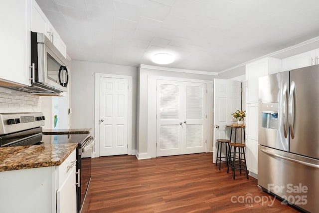 911 Elm St, Kannapolis, NC 28081 - kitchen with stainless steel appliances, dark wood-style flooring, white cabinetry, dark stone counters, and decorative backsplash