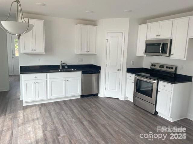 285 E Steele St, Salisbury, NC 28144 - kitchen featuring appliances with stainless steel finishes, dark countertops, dark wood-style flooring, and white cabinetry