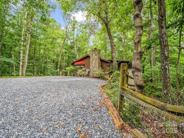 116 Chalet Rd, Lake Lure, NC 28746 - view of side of home with a chimney, gravel driveway, and a view of trees