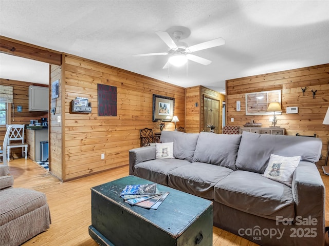 116 Chalet Rd, Lake Lure, NC 28746 - living room with wood walls, ceiling fan, light wood-type flooring, and a textured ceiling