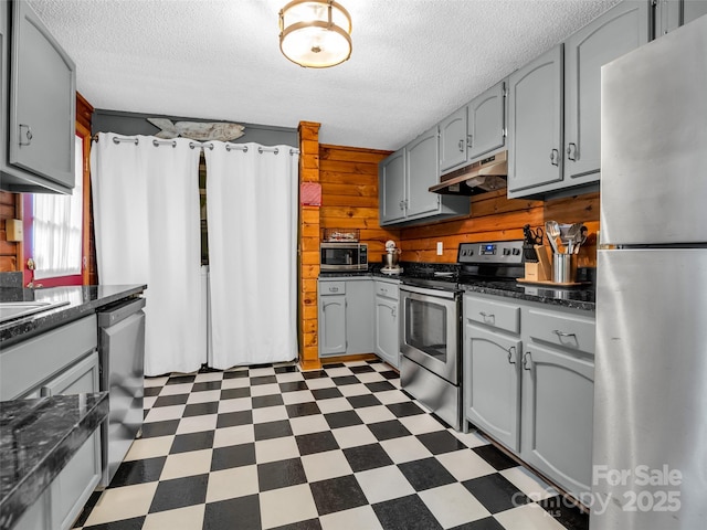 116 Chalet Rd, Lake Lure, NC 28746 - kitchen with appliances with stainless steel finishes, under cabinet range hood, dark flooring, gray cabinets, and wooden walls