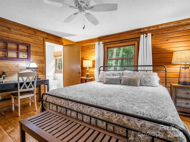 116 Chalet Rd, Lake Lure, NC 28746 - bedroom with multiple windows, a textured ceiling, wood finished floors, wood walls, and ensuite bathroom
