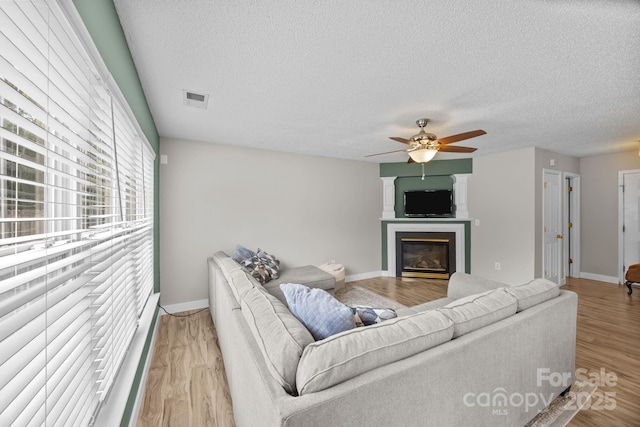 8009 Trotter Rd, Charlotte, NC 28216 - living area with ceiling fan, a glass covered fireplace, a textured ceiling, and wood finished floors