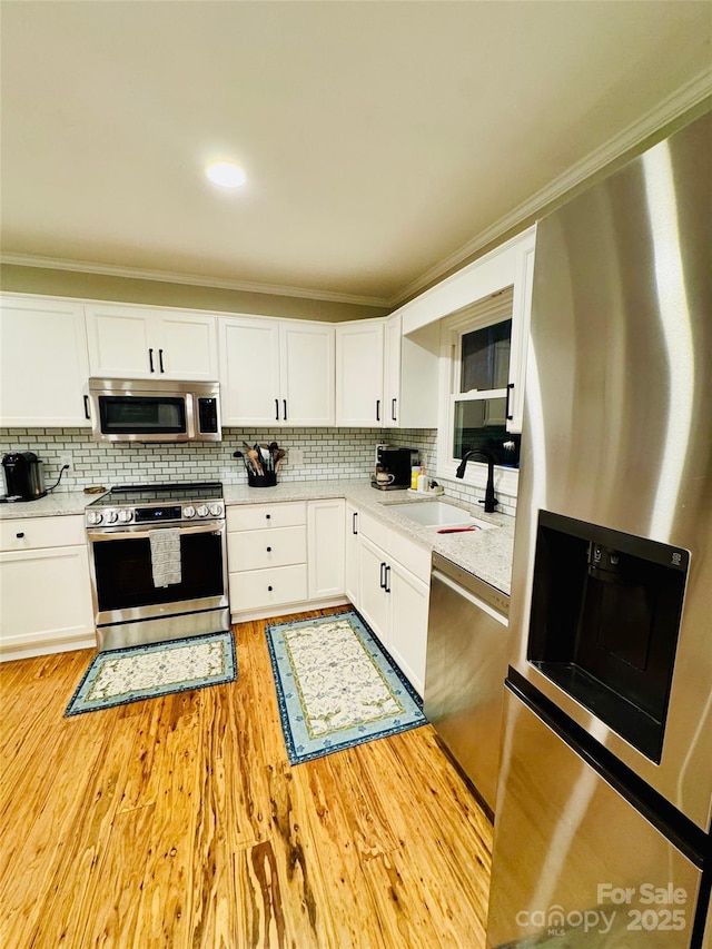 27 Walker Cove Rd, Black Mountain, NC 28711 - kitchen with stainless steel appliances, tasteful backsplash, white cabinets, crown molding, and light wood-style flooring