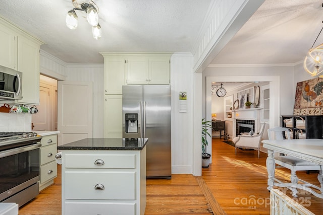 57 Patton Ct SE, Concord, NC 28025 - kitchen featuring stainless steel appliances, ornamental molding, light wood finished floors, a tiled fireplace, and a kitchen island