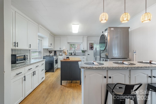700 Perkins St, Lowell, NC 28098 - kitchen featuring stainless steel appliances, white cabinets, light wood-type flooring, and backsplash