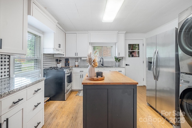 700 Perkins St, Lowell, NC 28098 - kitchen with appliances with stainless steel finishes, butcher block countertops, stacked washing machine and dryer, and white cabinetry