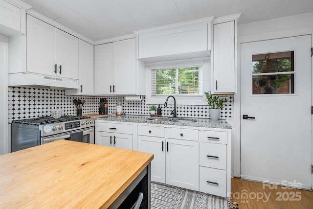 700 Perkins St, Lowell, NC 28098 - kitchen with under cabinet range hood, gas range, wooden counters, backsplash, and white cabinetry