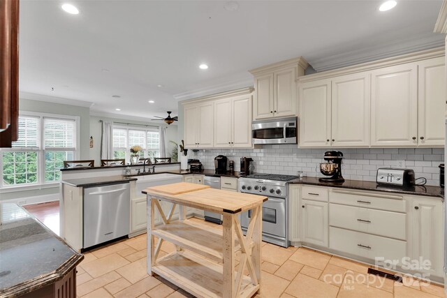 4552 Sawgrass Ct, Denver, NC 28037 - kitchen featuring stainless steel appliances, crown molding, a peninsula, decorative backsplash, and ceiling fan