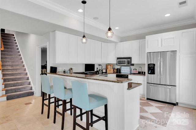 4552 Sawgrass Ct, Denver, NC 28037 - kitchen with appliances with stainless steel finishes, a kitchen breakfast bar, dark stone counters, white cabinets, and hanging light fixtures