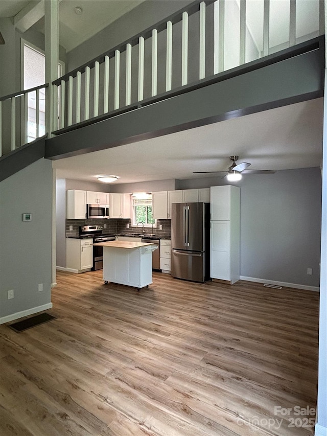 39 Moondust Dr, Waynesville, NC 28786 - kitchen with appliances with stainless steel finishes, open floor plan, white cabinetry, a towering ceiling, and a kitchen island