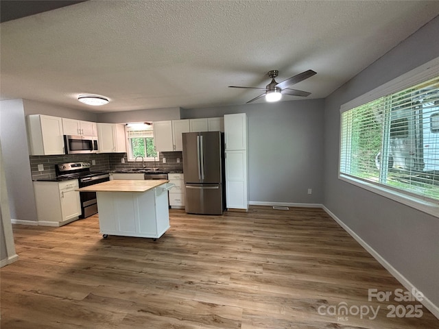 39 Moondust Dr, Waynesville, NC 28786 - kitchen featuring stainless steel appliances, backsplash, white cabinetry, a center island, and a textured ceiling