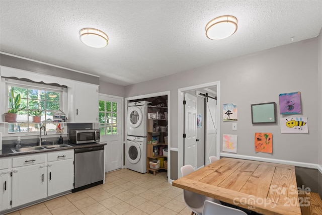 10108 Starwood Dr Unit 13, Charlotte, NC 28215 - kitchen with appliances with stainless steel finishes, stacked washer / drying machine, white cabinetry, a textured ceiling, and dark countertops