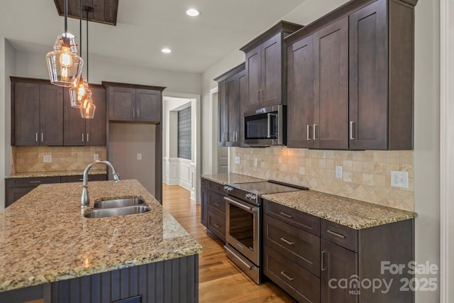 4930 Killian Crossing Dr, Denver, NC 28037 - kitchen featuring stainless steel appliances, light wood-type flooring, light stone countertops, dark brown cabinetry, and decorative light fixtures