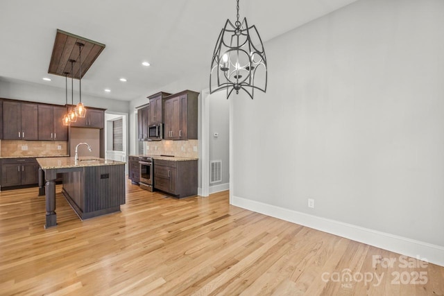 4930 Killian Crossing Dr, Denver, NC 28037 - kitchen featuring stainless steel appliances, tasteful backsplash, dark brown cabinetry, light stone countertops, and light wood finished floors