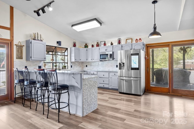 643 Lake Dr Unit 10, Lexington, NC 27292 - kitchen featuring appliances with stainless steel finishes, vaulted ceiling, a peninsula, a kitchen breakfast bar, and backsplash