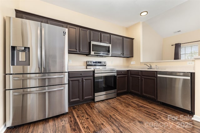 4208 Carl Parmer Dr, Harrisburg, NC 28075 - kitchen featuring appliances with stainless steel finishes, lofted ceiling, light countertops, dark brown cabinetry, and dark wood-type flooring