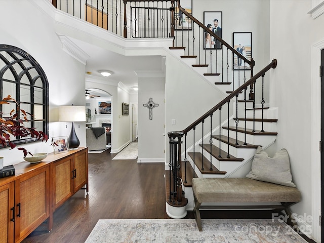 4032 Cambridge Hill Ln, Charlotte, NC 28270 - entryway featuring a high ceiling, crown molding, dark wood-type flooring, a warm lit fireplace, and stairs