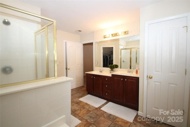 2418 Alaqua Ct, Matthews, NC 28105 - bathroom featuring a stall shower, stone finish flooring, double vanity, and a spacious closet