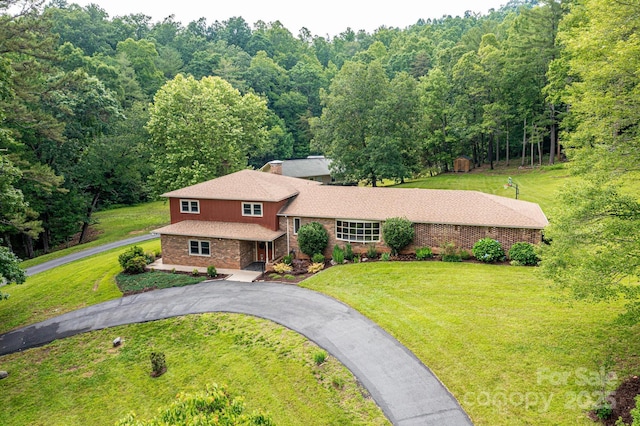 221 Roberts Ln, Lenoir, NC 28645 - tri-level home with brick siding, asphalt driveway, a front lawn, and a view of trees