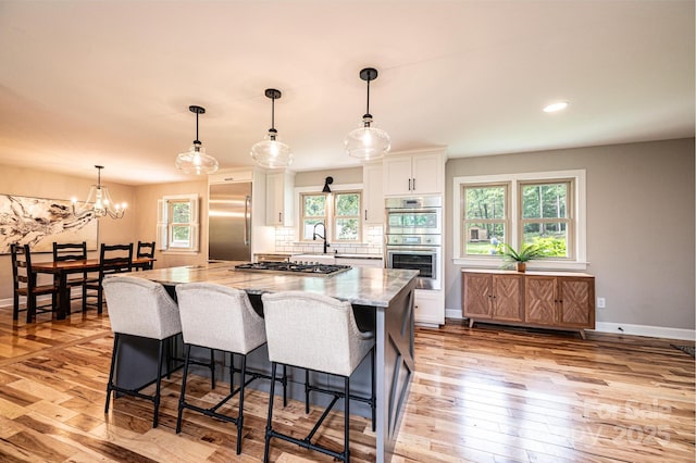 221 Roberts Ln, Lenoir, NC 28645 - kitchen with stainless steel appliances, white cabinets, a kitchen island, light stone countertops, and light wood-style floors