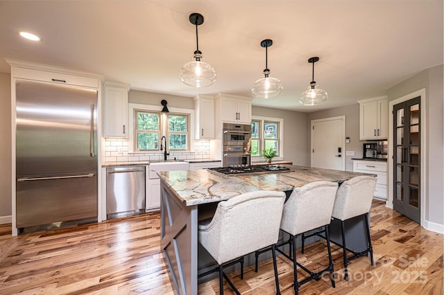 221 Roberts Ln, Lenoir, NC 28645 - kitchen featuring appliances with stainless steel finishes, white cabinetry, backsplash, light wood-type flooring, and a kitchen island