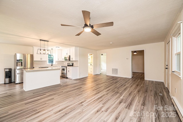 221 Roberts Ln, Lenoir, NC 28645 - unfurnished living room featuring a ceiling fan, light wood finished floors, a baseboard radiator, and a textured ceiling