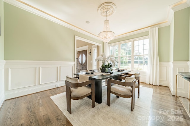 802 Capington Ln, Waxhaw, NC 28173 - dining area featuring crown molding, a chandelier, a decorative wall, light wood finished floors, and wainscoting