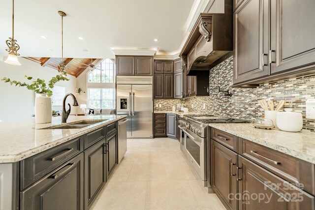802 Capington Ln, Waxhaw, NC 28173 - kitchen featuring premium appliances, tasteful backsplash, wall chimney exhaust hood, light tile patterned floors, and decorative light fixtures