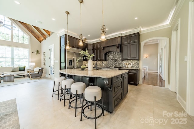802 Capington Ln, Waxhaw, NC 28173 - kitchen with arched walkways, built in refrigerator, backsplash, a kitchen breakfast bar, and light stone counters