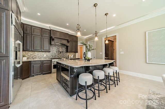 802 Capington Ln, Waxhaw, NC 28173 - kitchen with stainless steel appliances, backsplash, crown molding, a kitchen island with sink, and dark brown cabinetry