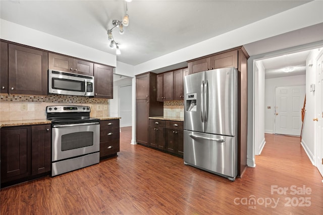 1230 Ridgebury Ter, Matthews, NC 28105 - kitchen featuring appliances with stainless steel finishes, dark brown cabinets, dark wood-style flooring, backsplash, and light stone countertops