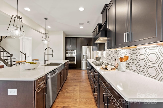 158 Nicholson Ln, Mooresville, NC 28115 - kitchen with stainless steel appliances, light wood-type flooring, a kitchen island with sink, premium range hood, and light countertops