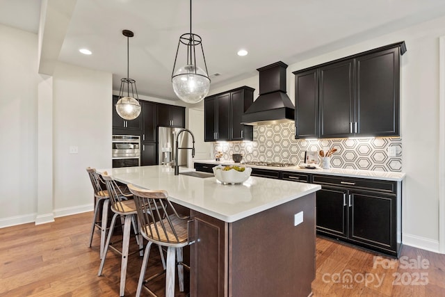 158 Nicholson Ln, Mooresville, NC 28115 - kitchen with premium range hood, a center island with sink, light wood finished floors, a breakfast bar, and recessed lighting