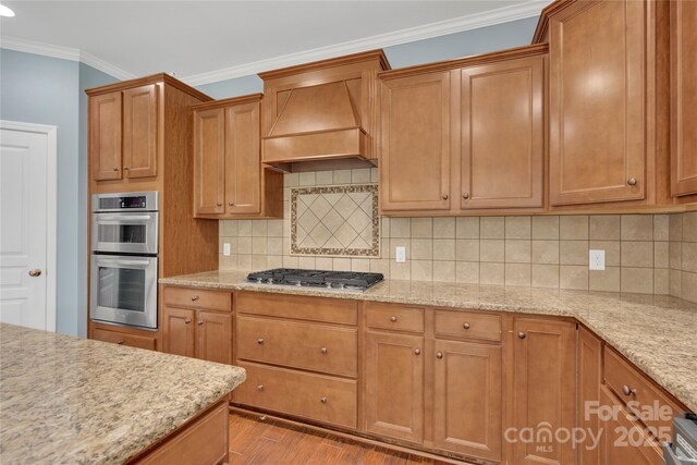 2805 Julian Glen Cir, Waxhaw, NC 28173 - kitchen with appliances with stainless steel finishes, premium range hood, crown molding, wood finished floors, and light stone counters