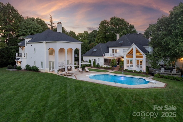 533 Valley Run Dr, Waxhaw, NC 28173 - back of property at dusk with a balcony, a patio, an outdoor pool, and a lawn