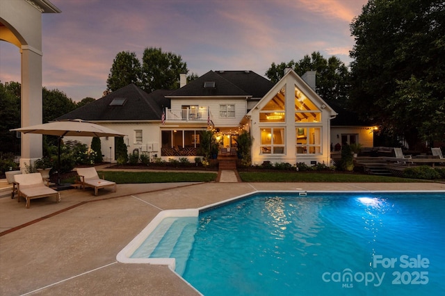 533 Valley Run Dr, Waxhaw, NC 28173 - back of property at dusk with an outdoor pool, a chimney, a patio, and a balcony