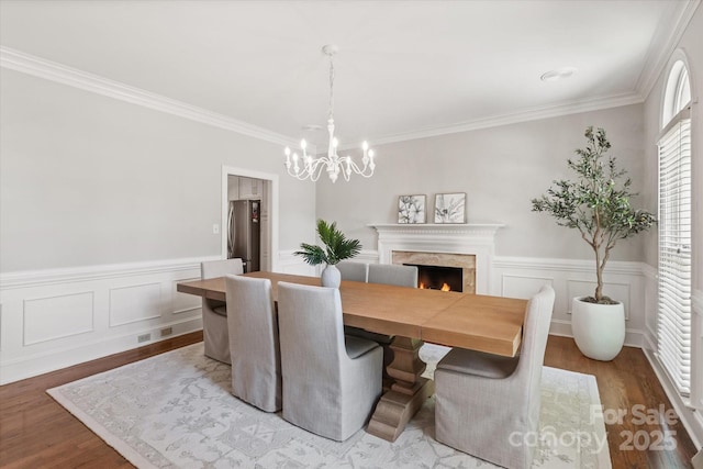 533 Valley Run Dr, Waxhaw, NC 28173 - dining room featuring a chandelier, wood finished floors, a premium fireplace, ornamental molding, and a wainscoted wall