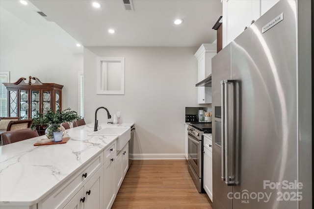 533 Valley Run Dr, Waxhaw, NC 28173 - kitchen with stainless steel appliances, a peninsula, white cabinetry, light wood-type flooring, and recessed lighting