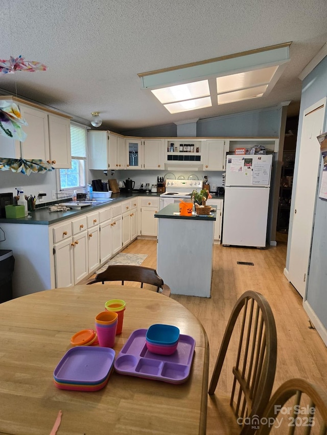 245 Waycross Dr, Rockwell, NC 28138 - kitchen featuring white appliances, dark countertops, light wood-style flooring, white cabinets, and vaulted ceiling