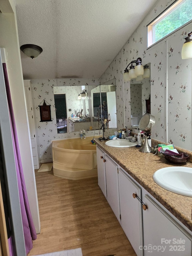 245 Waycross Dr, Rockwell, NC 28138 - full bathroom featuring wallpapered walls, a textured ceiling, wood finished floors, double vanity, and a bath
