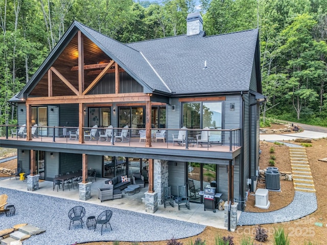 627 Cherry Hl Unit 201, Mill Spring, NC 28756 - back of house featuring a patio area, a shingled roof, a chimney, an outdoor living space, and a forest view